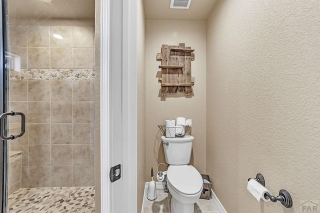 full bath featuring visible vents, a textured wall, toilet, a shower stall, and baseboards