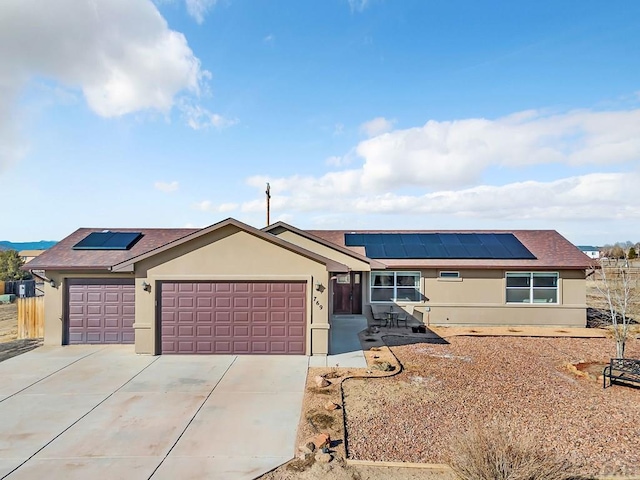 single story home featuring an attached garage, solar panels, concrete driveway, and stucco siding