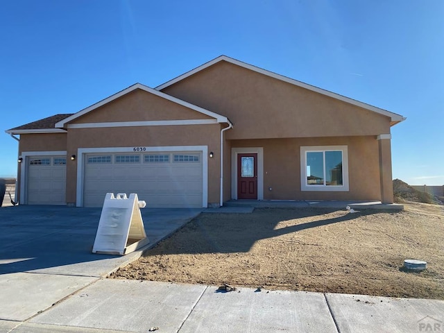 ranch-style home with a garage, concrete driveway, and stucco siding