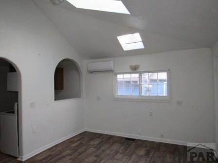 1119 Pine St, Pueblo, CO 81004 - unfurnished room with a skylight, a wall mounted air conditioner, dark wood-type flooring, baseboards, and vaulted ceiling
