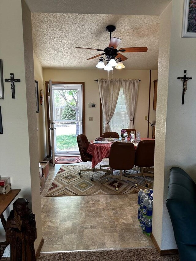 dining area featuring a textured ceiling, stone finish flooring, and a ceiling fan