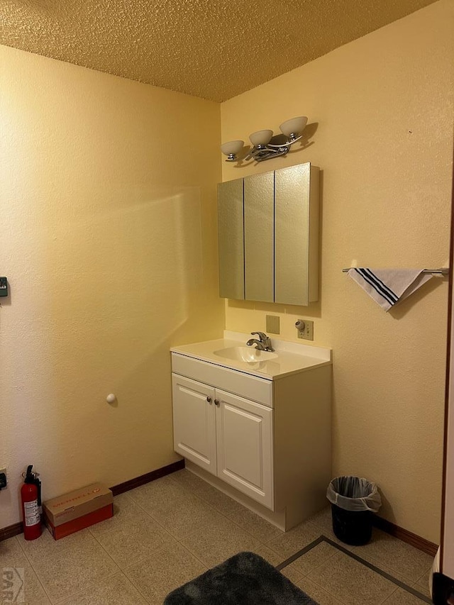 bathroom featuring a textured ceiling, vanity, and baseboards