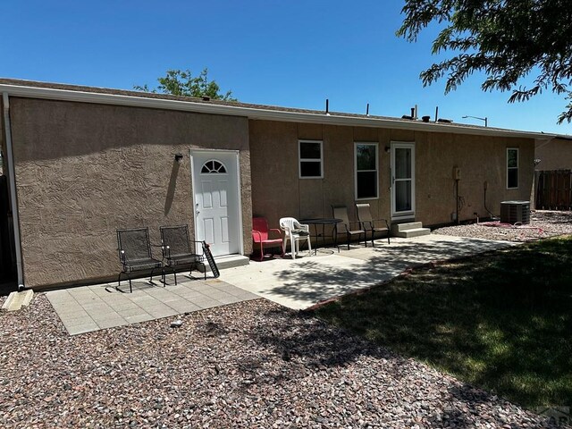 rear view of property featuring entry steps, central air condition unit, a patio area, and stucco siding