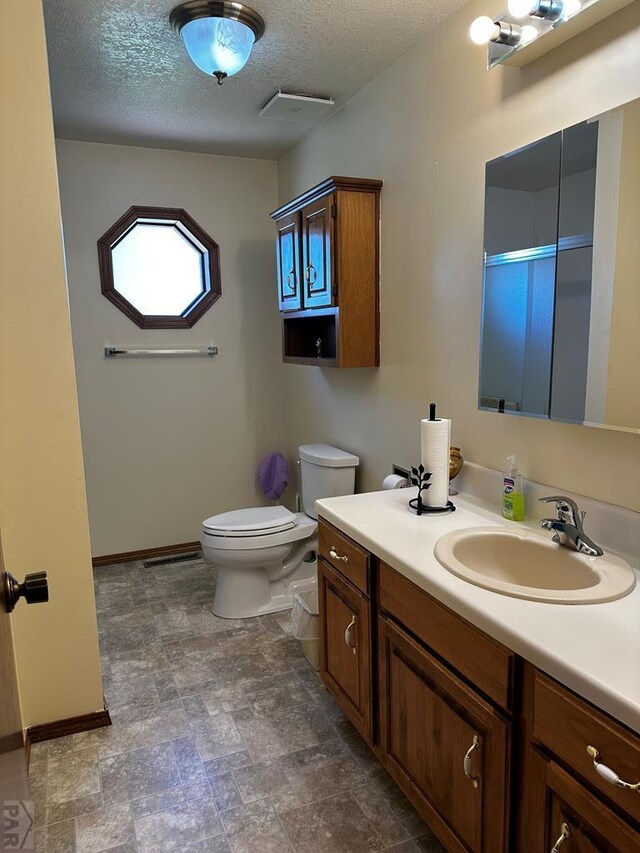 full bathroom featuring toilet, an enclosed shower, a textured ceiling, vanity, and baseboards