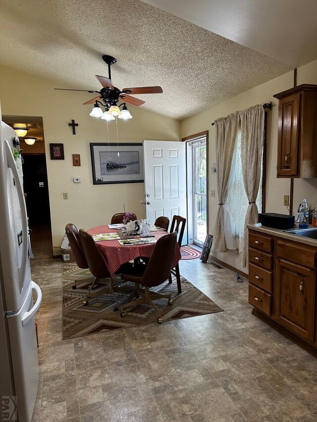 dining space with lofted ceiling, ceiling fan, and a textured ceiling