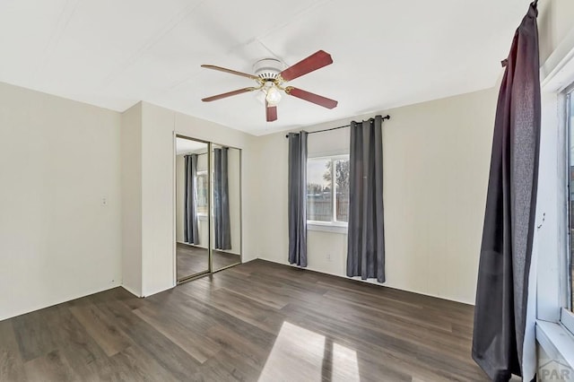 unfurnished bedroom featuring ceiling fan, a closet, and dark wood-type flooring