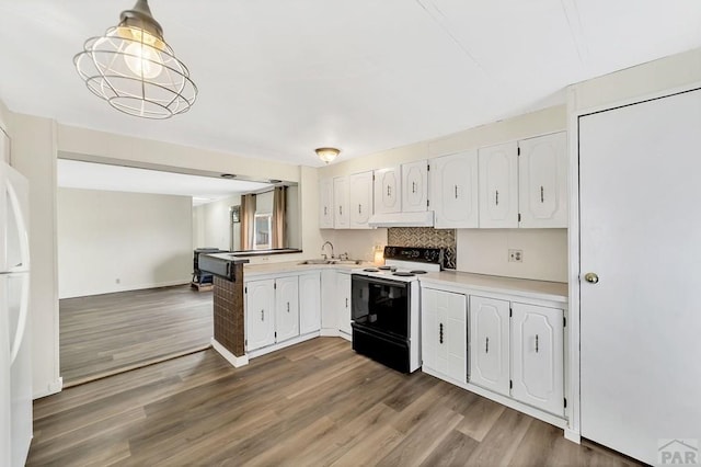 kitchen featuring electric stove, light countertops, hanging light fixtures, white cabinetry, and under cabinet range hood