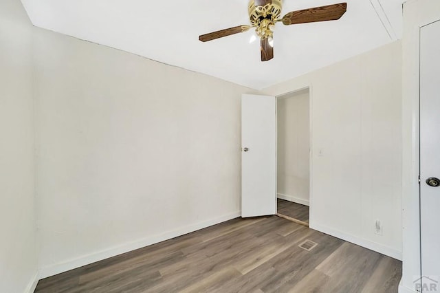 unfurnished room with dark wood-style floors, visible vents, baseboards, and a ceiling fan