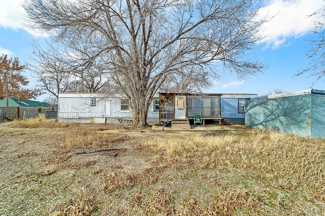 rear view of house featuring entry steps and fence