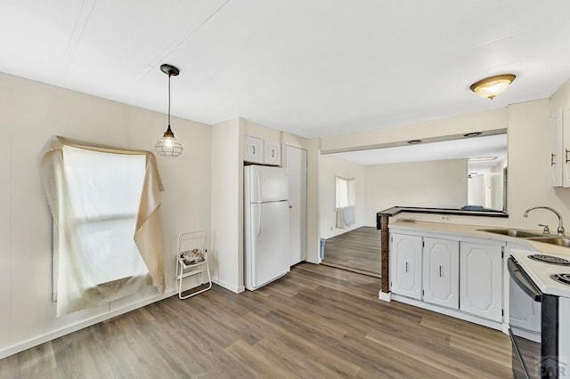 kitchen with a sink, white cabinets, light countertops, electric stove, and freestanding refrigerator