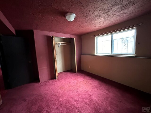 unfurnished bedroom with a textured ceiling, carpet floors, and a closet