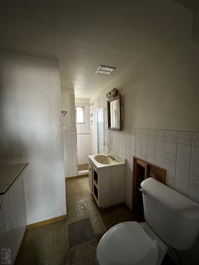 bathroom with toilet, tile walls, and vanity