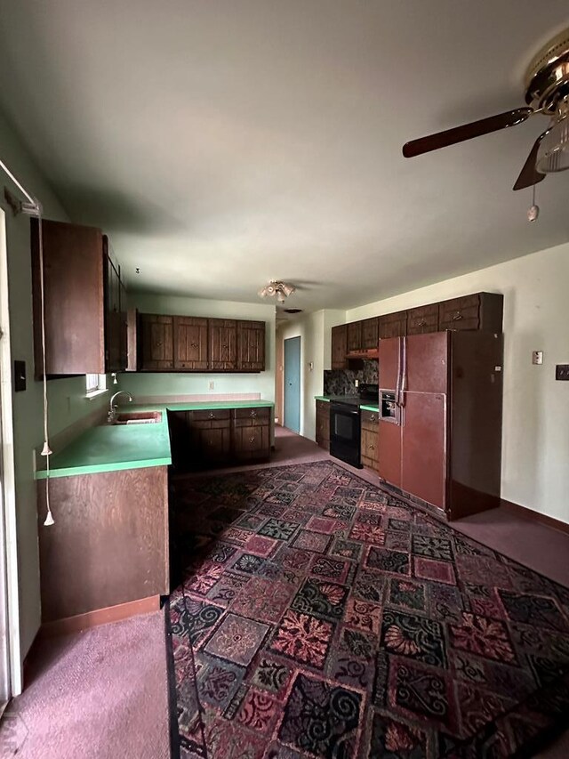 kitchen with dark brown cabinets, light countertops, a sink, and freestanding refrigerator