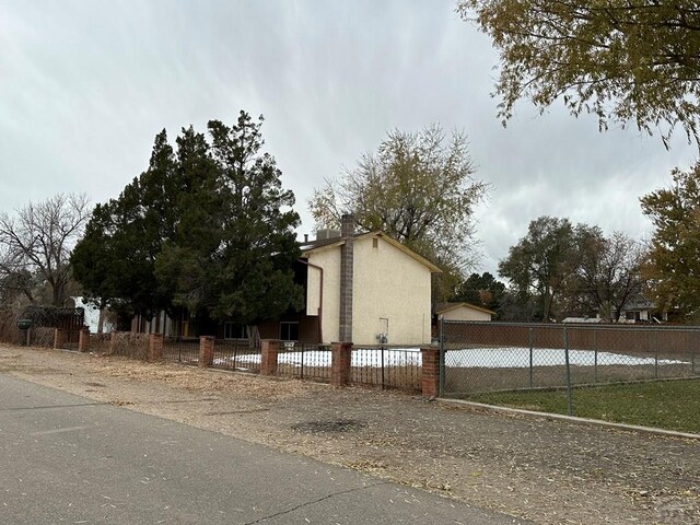 view of side of home with a fenced front yard and stucco siding