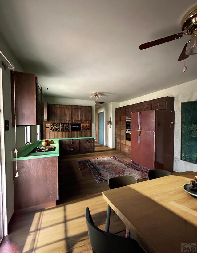 kitchen with light wood-type flooring, ceiling fan, stainless steel double oven, and freestanding refrigerator