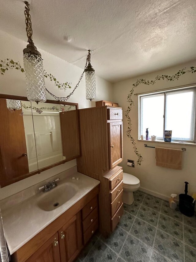 bathroom with baseboards, toilet, vanity, and a textured ceiling