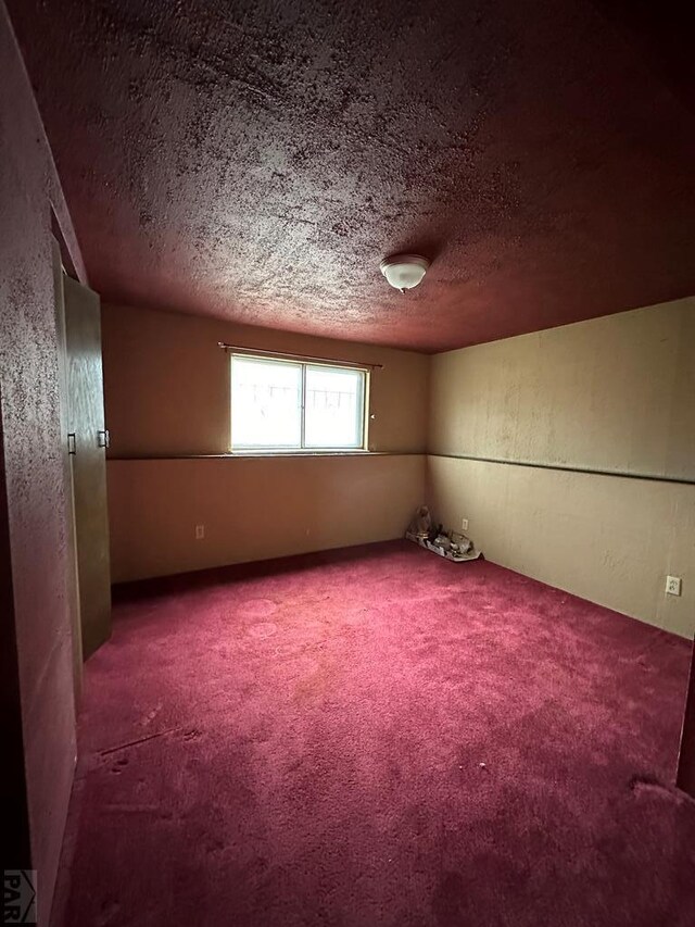 carpeted empty room with a textured ceiling