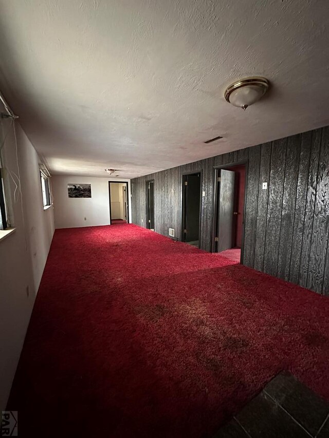 home theater room with visible vents, carpet flooring, wood walls, and a textured ceiling