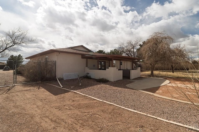 view of side of property featuring a patio area, stucco siding, a gate, and fence