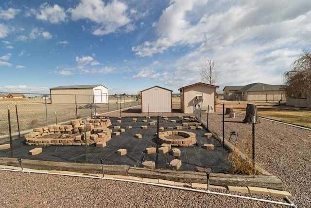 view of yard with an outbuilding, a storage shed, an outdoor fire pit, and fence