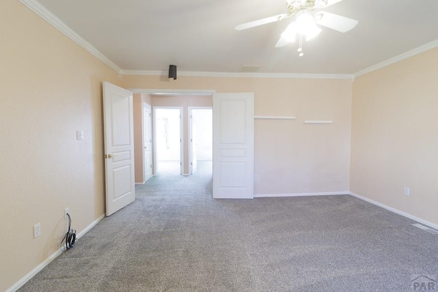 spare room featuring carpet flooring, baseboards, a ceiling fan, and crown molding