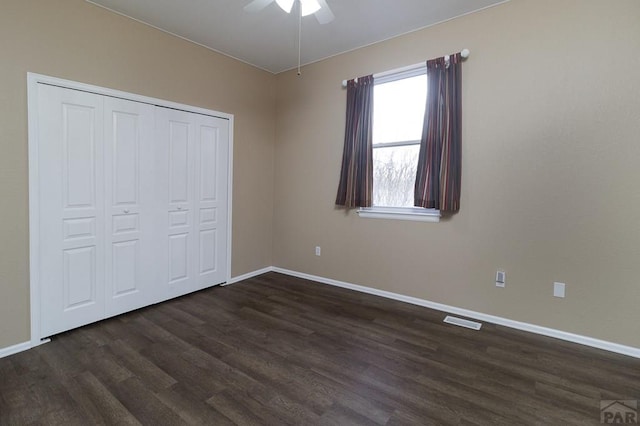 unfurnished bedroom featuring baseboards, visible vents, and dark wood-style flooring