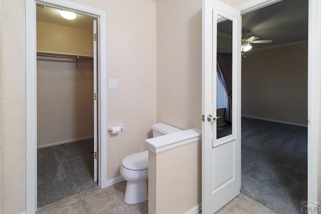 bathroom featuring tile patterned floors, toilet, crown molding, baseboards, and ceiling fan