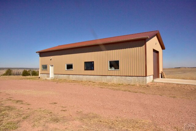 view of home's exterior featuring a garage, dirt driveway, metal roof, and an outbuilding