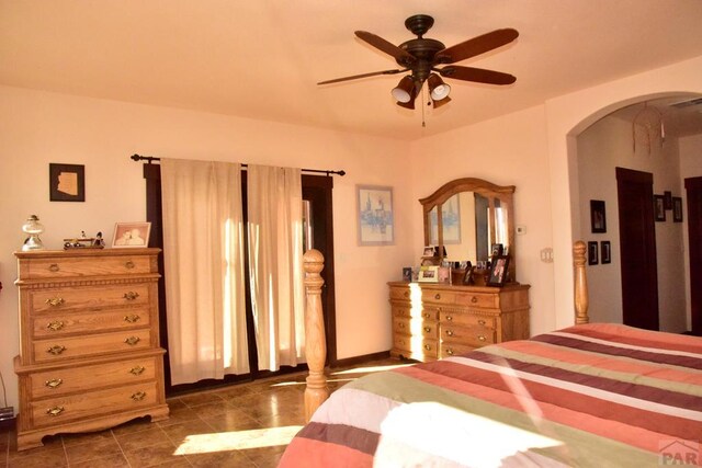 bedroom with a ceiling fan, arched walkways, visible vents, and dark tile patterned flooring