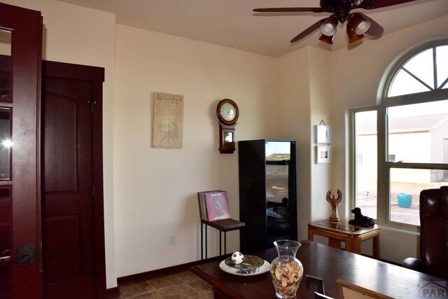 living area with ceiling fan and baseboards