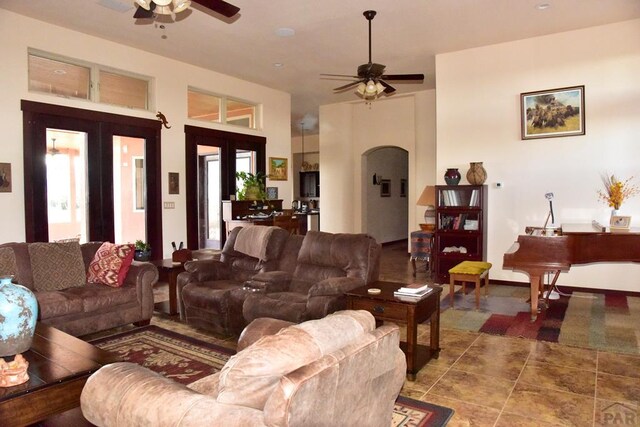 living room with baseboards, arched walkways, a ceiling fan, and french doors