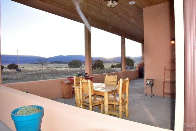 view of patio featuring outdoor dining space, a rural view, and a mountain view