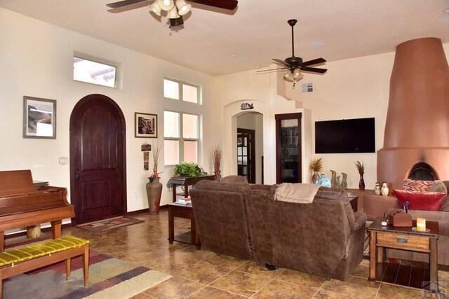 living room featuring arched walkways, a towering ceiling, and a ceiling fan