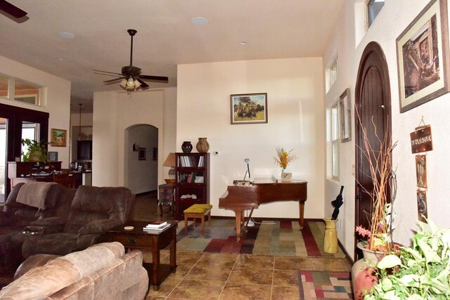 living area featuring arched walkways, ceiling fan, and tile patterned flooring