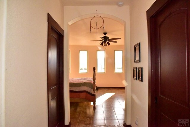 corridor with arched walkways and tile patterned floors