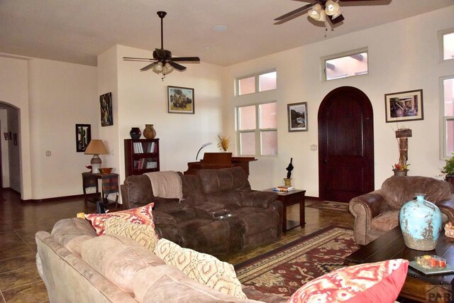 living area with arched walkways, ceiling fan, and dark tile patterned floors