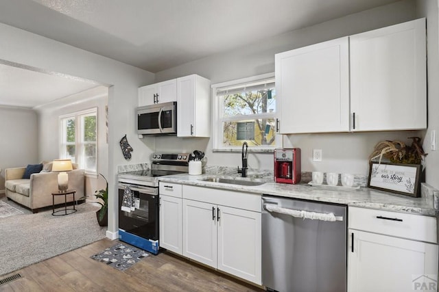 1934 E 11th St, Pueblo, CO 81001 - kitchen with appliances with stainless steel finishes, a sink, wood finished floors, open floor plan, and white cabinetry