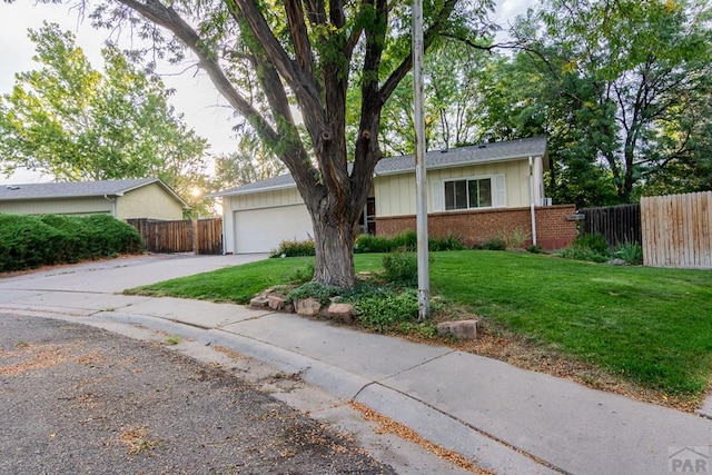 single story home featuring brick siding, fence, a front yard, and driveway