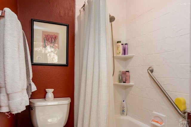 bathroom with toilet, shower / bathtub combination with curtain, and a textured wall