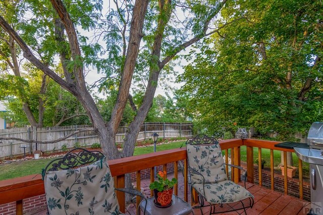 wooden deck featuring a grill, a yard, and a fenced backyard