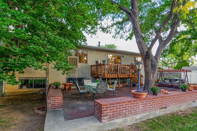 back of house featuring a deck, stucco siding, fence, a patio, and outdoor dining space