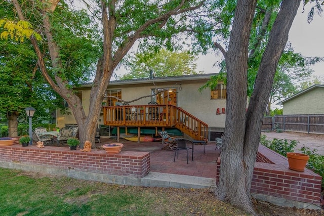 back of house featuring stucco siding, fence, a deck, and a patio area