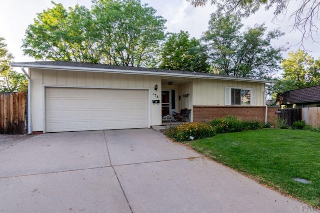 single story home featuring brick siding, fence, driveway, a front lawn, and an attached garage
