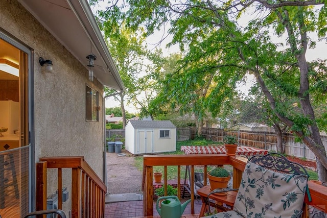 wooden deck featuring an outdoor structure, a fenced backyard, a patio area, and a storage shed