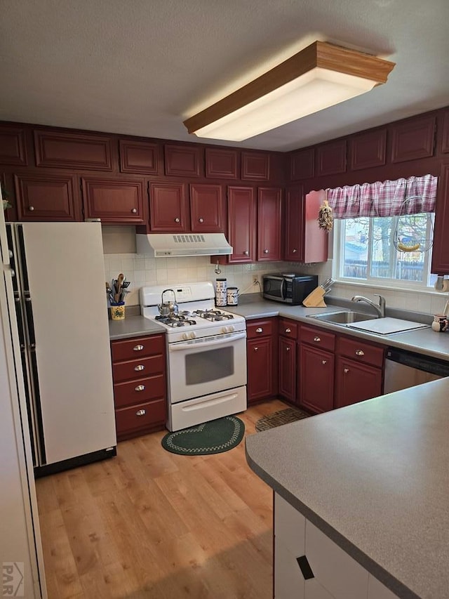 178 Macneil Pl, Pueblo, CO 81001 - kitchen featuring light wood finished floors, reddish brown cabinets, white appliances, under cabinet range hood, and decorative backsplash