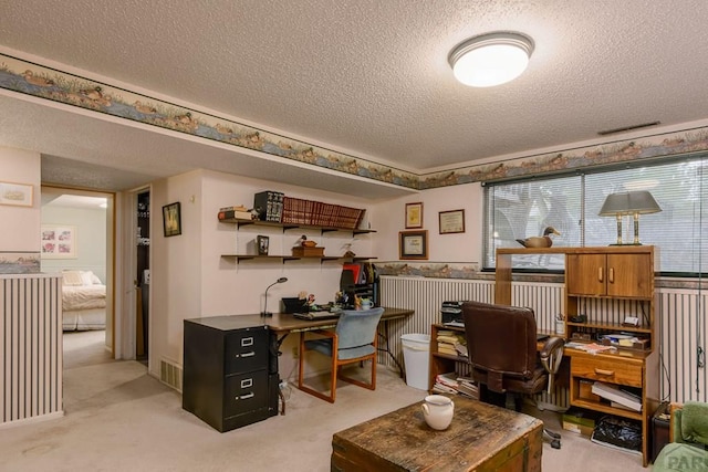 home office with a textured ceiling, visible vents, light carpet, and a healthy amount of sunlight