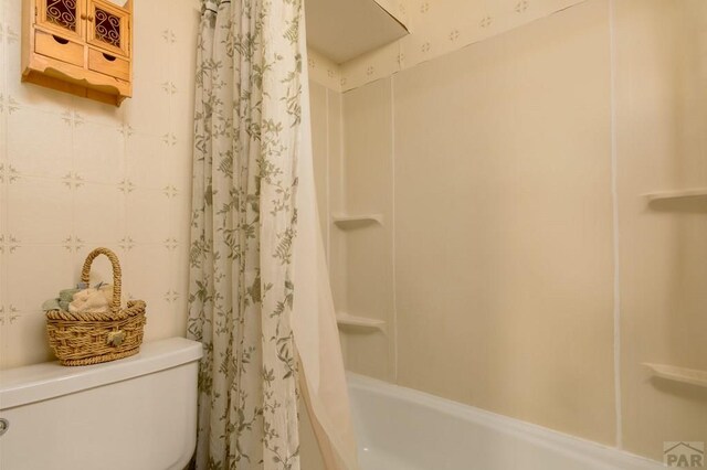 bathroom featuring shower / bathtub combination with curtain and toilet