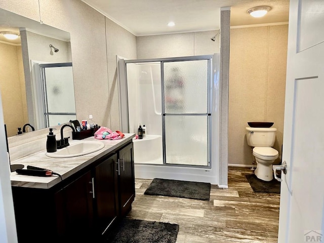 bathroom featuring a shower stall, crown molding, wood finished floors, and vanity