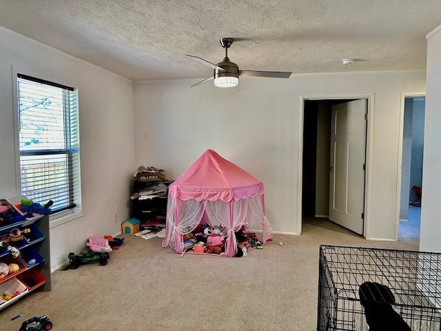 playroom featuring light colored carpet, ceiling fan, a textured ceiling, and baseboards