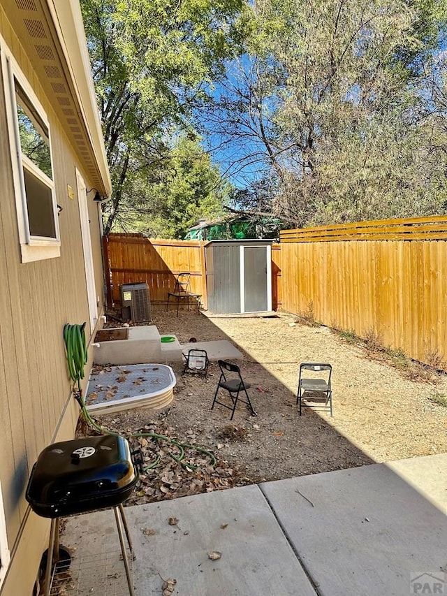 view of yard with an outbuilding, a patio, central air condition unit, a shed, and a fenced backyard